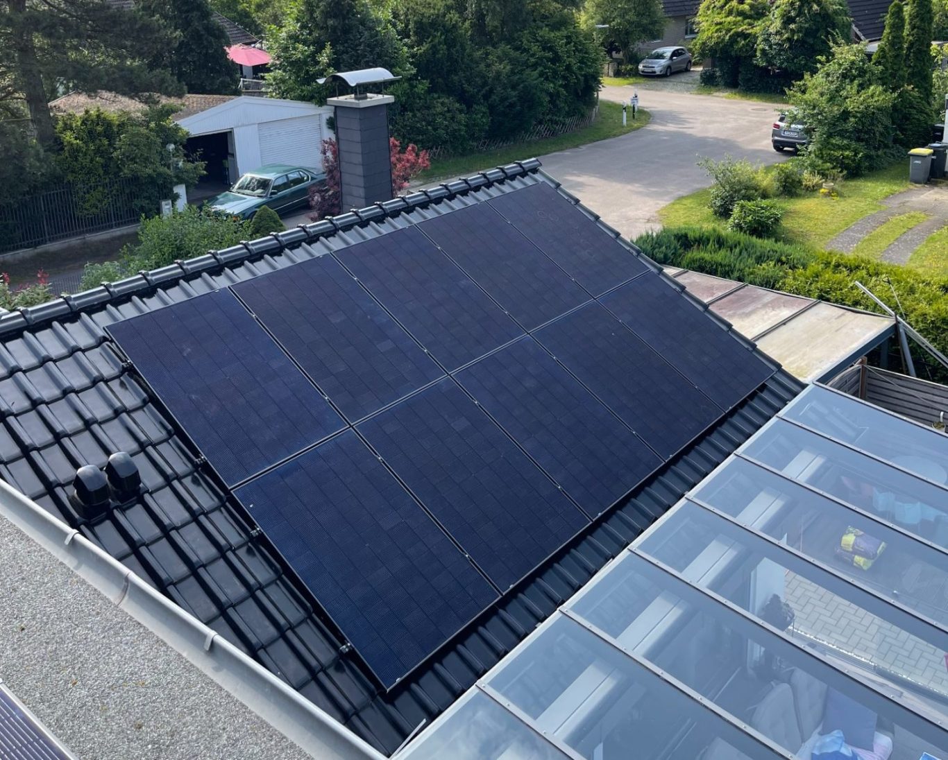 Sun Earth Photovoltaik-Module 435Watt full Black Dach mit Solarpanels, umgeben von Bäumen und einer ruhigen Nachbarschaft.